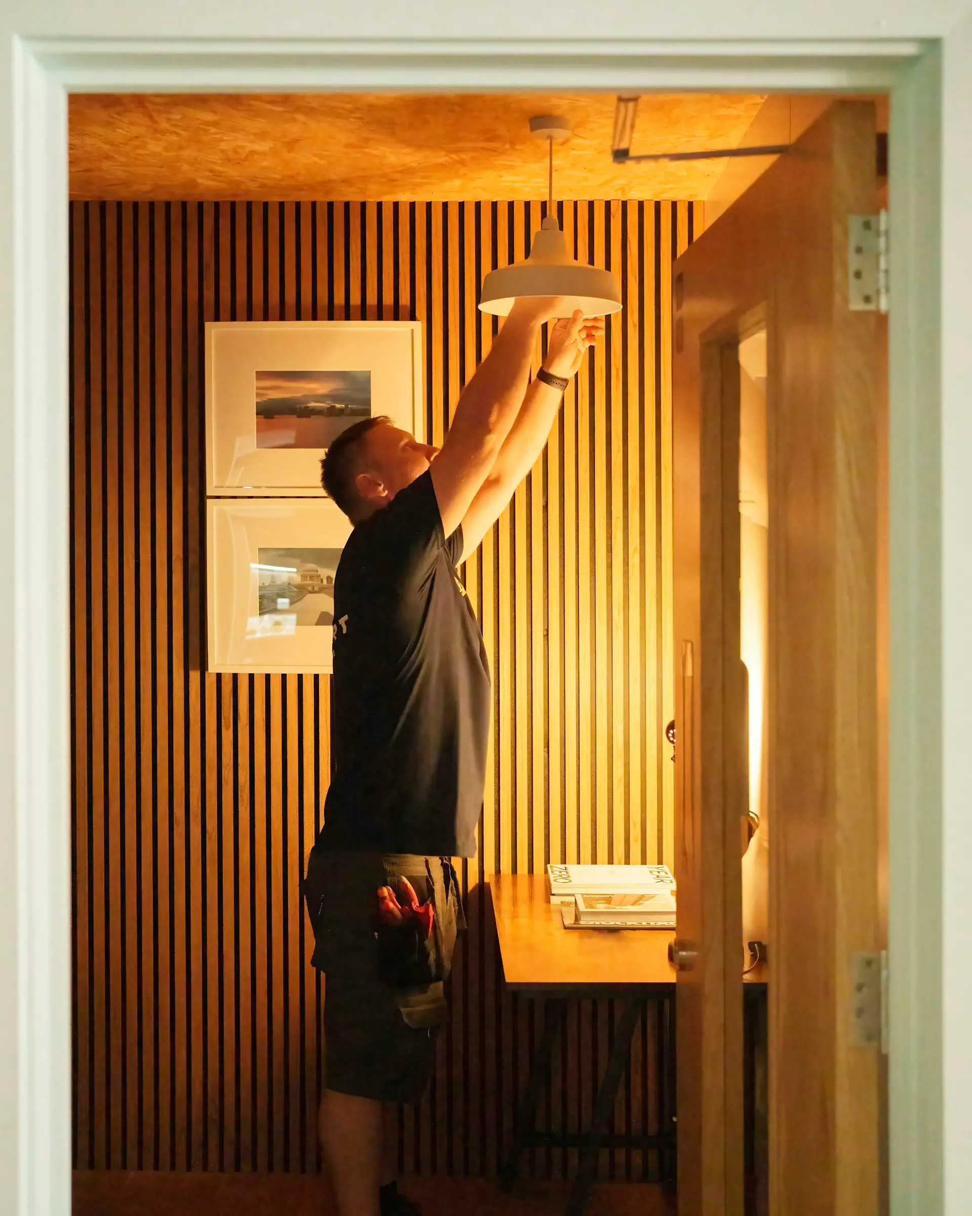 Électricien posant un luminaire dans un séjour boisé